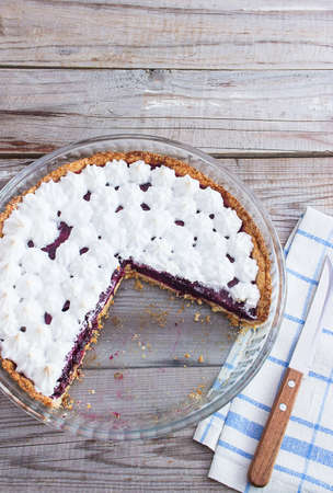 Meringue covered berry tart wooden rough table.