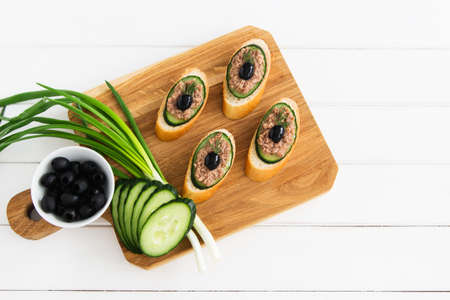 Open tuna sandwiches with cucumber on cutting board.