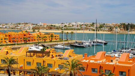 PORTIMAO, PORTUGAL - MAI 24, 2019: View on the residential area of Portimao with colorful houses and pier with white sailboats in Algarve, Portugal.のeditorial素材