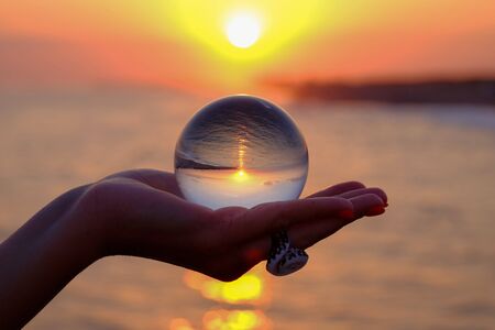 Crystal ball in the palm with an inverted reflection of the sunset on the sea in Turkey in Kizilagac...