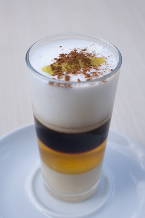 Traditional Canarian coffee Barraquito with separated layers of milk condensed and liquor on blurred...