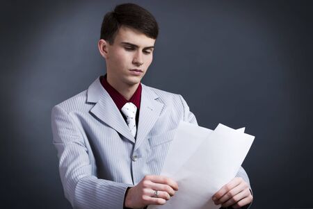 dark studio portrait of business man with documents in his handsの写真素材