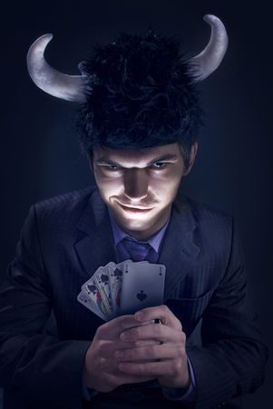 dark studio portrait of an evil man in a hat with horns and a cardsの写真素材