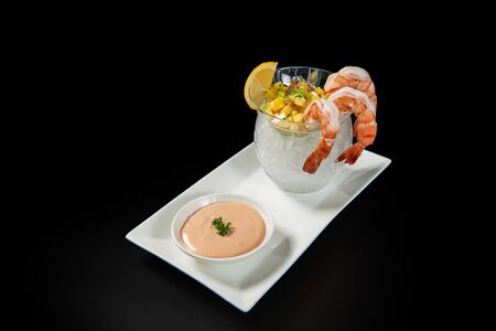 Glass with appetizer shrimp cocktail and salsa sauce on black background and copy spaceの写真素材