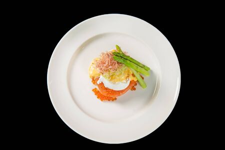 Delicious breakfast with Eggs Benedict and salmon caviar (Ikura) on the black background, top viewの写真素材