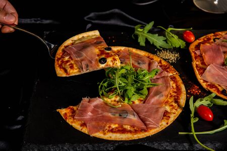Pizza Jamon IbÃ©rico and Rocket salad served on slate table, black background, top viewの写真素材