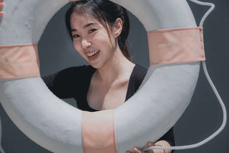 Young beautiful woman portrait with swim ring isolated on grey background outdoor conceptの写真素材