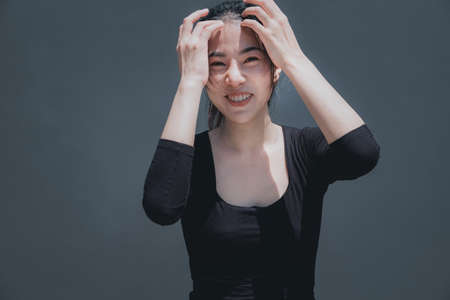 Young beautiful asian woman smile on face on the grey black ground outdoor natural lightの写真素材