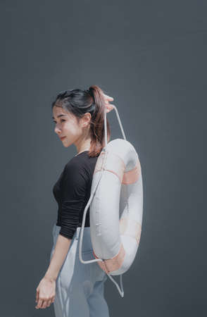 Young beautiful woman portrait with swim ring isolated on grey background outdoor conceptの写真素材