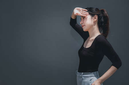Young beautiful asian woman cover her face with hand from the sun outdoors, grey background with copy spaceの写真素材