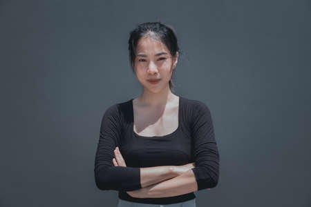Young beautiful woman crossed her arms with upset face, grey background with copy spaceの写真素材