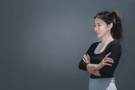 Young beautiful asian woman portrait smiling and cross her arms, grey background with copy spaceの写真素材