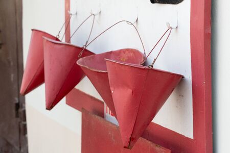 red bucket to fight the fire. a red bucket is hanging on a fire shieldの写真素材