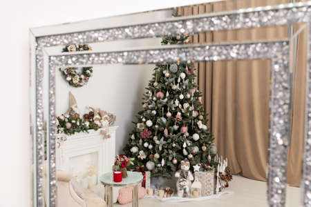 Reflection in the mirror of the christmas tree. Tall Christmas tree decorated in blue. There are large boxes with gifts under the tree.の写真素材