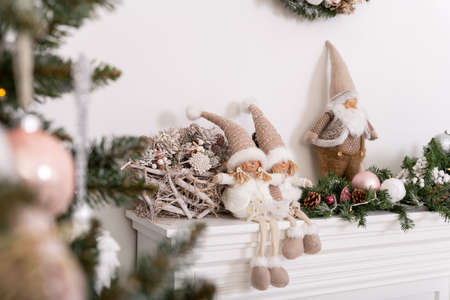 Christmas decorated tree in soft pink colors against the background of white classic fireplace with Christmas decorations. Details of New Year festive living room interiorの写真素材