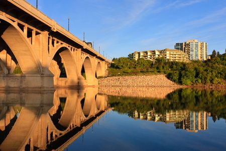 The Broadway Bridge in Saskatoon reflecting in the calm waters of the Saskatchewan River.の写真素材