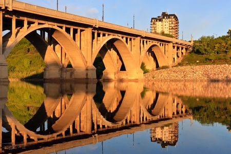The Broadway Bridge in Saskatoon reflecting in the calm waters of the Saskatchewan River.の写真素材