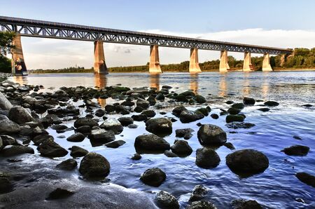 Old iron train bridge over the South Saskatchewan River in Saskatoon, Canadaの写真素材
