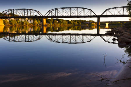 The Victoria Bridge in Saskatoon reflecting in the calm waters of the Saskatchewan River.の写真素材