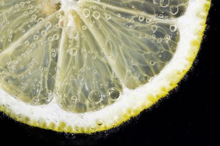 Thin slice of yellow lemon in soda water to form the bubblesの写真素材