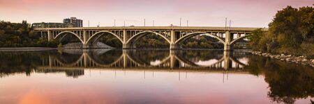 Concrete bridge reflecting in the perfect reflection in the water of the calm riverの写真素材