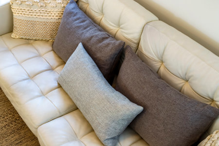 A white couch with a gray and brown pillow on it. The pillow is placed in the middle of the couch,...