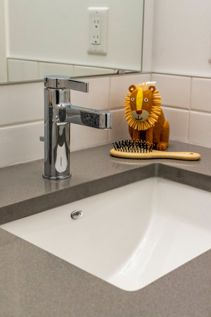 A sink with a lion figurine on top of it. The sink is white and the lion is yellowの写真素材