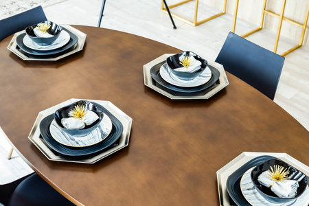 A table with a variety of plates and bowls, including a black and white plate with a flower designの写真素材