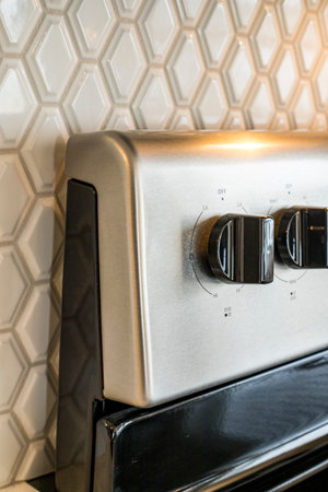 A silver stove top with a black handle and a white background. The stove is turned off