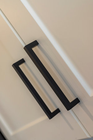 The handles of a cabinet door are black. The handles are square and have a black designの写真素材
