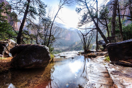 A beautiful mountain landscape with a river running through it. The water is calm and the sky is cloudyの写真素材
