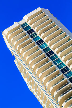 A tall building with a blue sky in the background. The building has a unique shape and is made of...