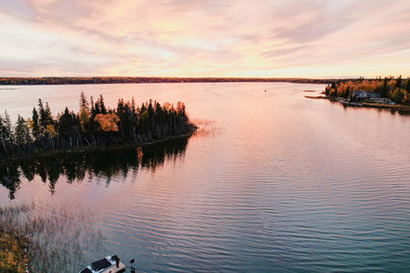 A beautiful lake with a sunset in the background. The water is calm and the sky is filled with orange and pink huesの写真素材