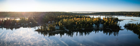 A beautiful lake with a forest in the background. The sky is blue and the sun is shiningの写真素材