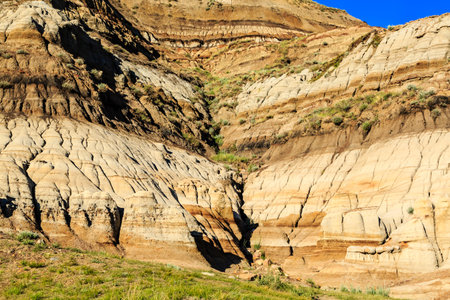 A rocky hillside with a small valley in the middle. The hillside is covered in rocks and dirt, and the valley is filled with grassの写真素材