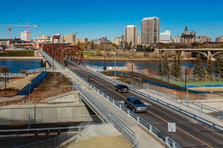 A bridge over a river with cars driving on it. The cars are driving on the road and there are a few...