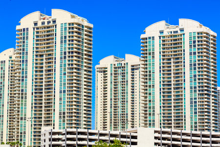 A row of tall buildings with a clear blue sky in the background. The buildings are white and have...