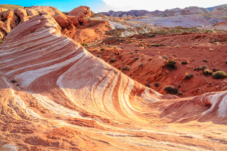 A rocky, red and white landscape with a large, white and red hill. The hill is covered in grass and has a wave-like appearanceの写真素材