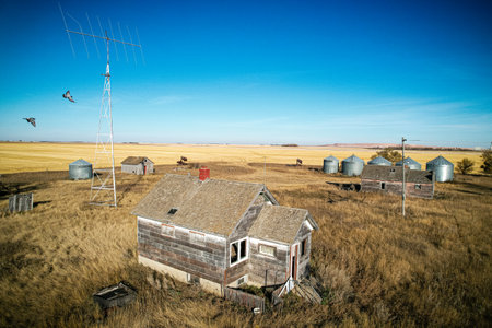 A house is in the middle of a field with a few other houses and a barn. The house is old and...