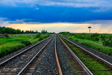 The train tracks are empty and the sky is cloudy. Scene is calm and peaceful, as there are no people...
