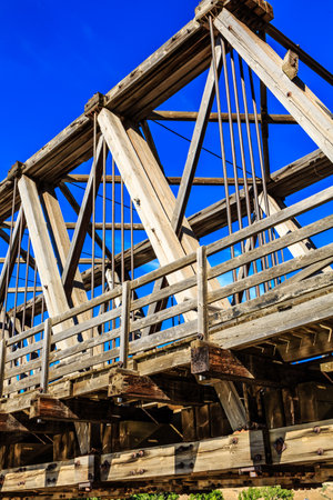 A bridge with a blue sky in the background. The bridge is old and has a rustic appearance