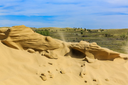 A vast, sandy desert with a large rock formation in the center. The sky is clear and cloudless,...