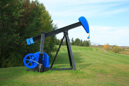 A blue and black oil rig is on a grassy hill. The rig is a sculpture and is not functional