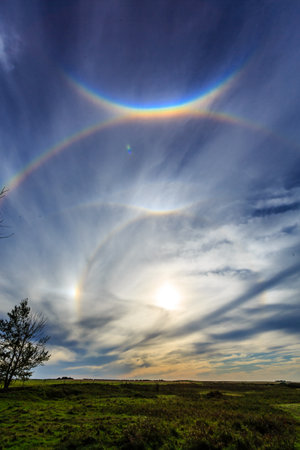 The sky is blue with clouds and a rainbow. The clouds are white and the rainbow is red, yellow, and blueの写真素材
