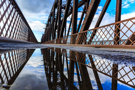 The bridge is made of metal and has a lot of water on it. The water is reflecting the sky and the bridgeの写真素材