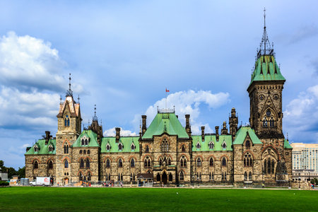 A large building with a green roof and a clock tower. The building is surrounded by a grassy areaの写真素材