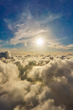 The sky is blue with a few clouds and the sun is shining brightly. The clouds are fluffy and white, and the sun is casting a warm glow on the clouds. The scene is peaceful and sereneの写真素材