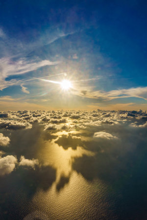 The sun is shining on the water, creating a beautiful reflection. The sky is filled with clouds, giving the scene a serene and peaceful atmosphereの写真素材