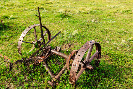 A rusted old tractor is sitting in a field of grass. The scene has a nostalgic and somewhat melancholic moodの写真素材
