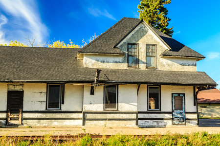 The old house has a lot of windows and a black roof. The house is empty and abandoned